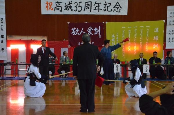 剣道の試合で、2人の選手が審査員と来賓者の前で蹲踞の姿勢をとっている写真